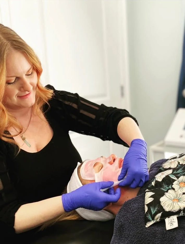 Elina performing a facial treatment on a client in her studio