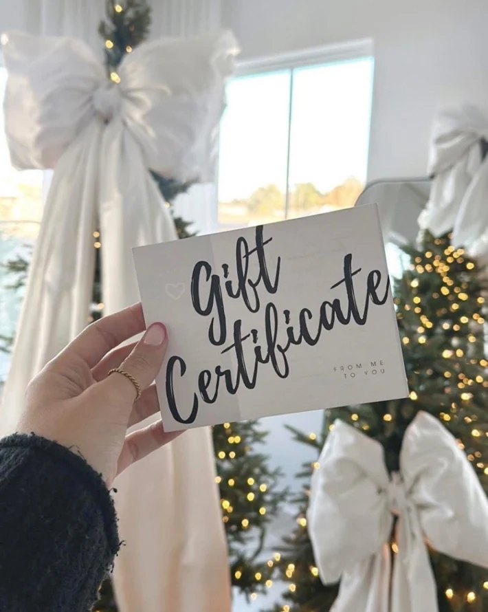 Gift certificate photo held in front of decorated Christmas trees